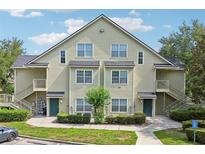 Two-story condo building featuring a light green exterior, symmetrical windows, and landscaped grounds at 3721 S Lake Orlando Pkwy # 05, Orlando, FL 32808