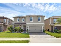 Charming two-story home with a manicured lawn and a brick-paved driveway leading to a two-car garage at 455 Lazio Cir, Debary, FL 32713