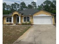 Charming single-story home featuring a two-car garage, well-manicured lawn, and inviting architectural details at 701 Twin Lake Ave, Deltona, FL 32738