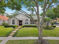 Charming single-story home featuring a well-manicured lawn, lush landscaping, and a distinctive tiled roof at 7698 Mount Carmel Dr, Orlando, FL 32835