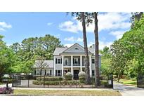 Stately two-story home featuring classic columns, black shutters, an iron fence, and lush landscaping at 830 Miami Springs Dr, Longwood, FL 32779