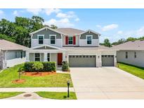 Two-story home with a three car garage, landscaped front yard, gray trim, and red shutters at 10249 Spring Lake Dr, Clermont, FL 34711