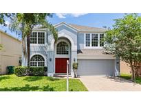 Charming two-story home features a red front door, arched entryway, and well-maintained landscaping at 12917 Grovehurst Ave, Winter Garden, FL 34787