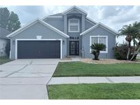 Charming two-story home featuring a well-manicured lawn and a two-car garage at 14400 Saint Georges Hill Dr, Orlando, FL 32828