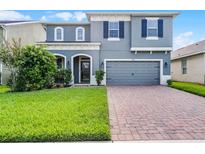 Charming two-story home with a well-manicured lawn and inviting brick driveway at 1553 Caterpillar St, St Cloud, FL 34771