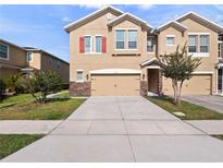 Two story home with a two car garage, stone accents, tan exterior paint and red shutters at 1610 Mohegan Blvd, Kissimmee, FL 34744
