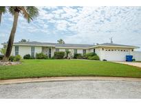 Inviting single-story home featuring a well-manicured lawn and attached two-car garage at 2 Pirates Cv, Ormond Beach, FL 32176