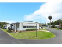 Well-maintained manufactured home with awnings and landscaped front yard in a vibrant 55+ community at 229 Rue De Fontaine, Tavares, FL 32778