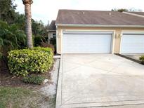View of the garage and driveway of this tan house with manicured landscaping at 2299 Hawks Cove Cir, New Smyrna Beach, FL 32168