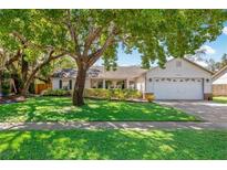 Charming single-story home featuring a lush green lawn, mature trees, and a welcoming two-car garage at 4235 Shades Crest Ln, Sanford, FL 32773