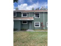 Exterior shot of a green two-story townhouse with a red tile roof, windows, and landscaping at 4503 Oak Arbor Cir, Orlando, FL 32808