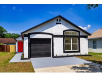 Charming one-story home featuring a black garage door and a red front door at 6856 Ebans Bend, Orlando, FL 32807