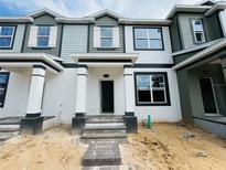 New construction townhome featuring gray and white siding, black trim, and a covered entry with stone steps at 15345 Burgtheater Dr, Winter Garden, FL 34787