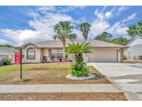 Inviting single-story home with a two-car garage and well-manicured landscaping featuring charming palm trees at 15628 Hidden Lake Cir, Clermont, FL 34711
