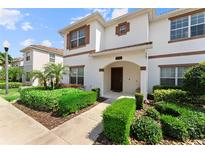 Beautifully landscaped white townhome with brown trim and arched entryway in a well-maintained community at 1596 Moon Valley Dr, Davenport, FL 33896