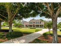 Inviting home featuring a circular driveway and manicured lawn, framed by mature trees at 17631 Vista Belle Ct, Montverde, FL 34756