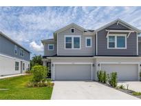 Charming townhome featuring a two-car garage, manicured landscaping, and stylish gray exterior at 1915 Terrapin Rd, Ocoee, FL 34761