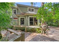 Two-story home with wood deck, surrounded by lush greenery and mature trees in a secluded setting at 4107 Gabriella Ln, Winter Park, FL 32792