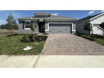Charming single-Gathering home features a gray exterior, a two-car garage and a brick paver driveway at 5262 Teirgarten St, St Cloud, FL 34771