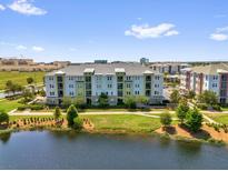 A multi-Gathering, multi-level building sits by a pond with trees and blue skies above at 7573 Laureate Blvd # 1-404, Orlando, FL 32827