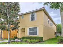 Two story home boasts a yellow exterior, white trim, and a well-manicured lawn at 8989 Cuban Palm Rd, Kissimmee, FL 34747