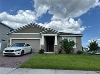 Charming single-story home featuring a well-maintained lawn, two car garage and brick-paved driveway at 1141 Lakeshore Breeze Pl, Kissimmee, FL 34747