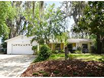 Charming home featuring a spacious front yard with mature trees and an attached two-car garage at 6105 Lost Tree Court, Orlando, FL 32808