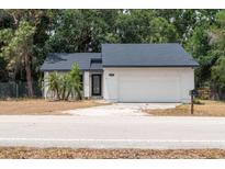 Charming single-story home featuring a white exterior, a two-car garage, and well-maintained landscaping at 6345 Hatcher Rd, Lakeland, FL 33811