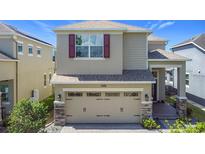 Two-story home featuring a two-car garage, neutral paint, and decorative stone accents at 10658 Bannan St, Orlando, FL 32832