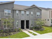 Modern townhome exterior featuring a stone facade, neutral stucco, and well manicured landscaping at 1632 Tropical Palms Circle, Kissimmee, FL 34747