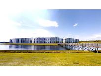 Modern condo complex with pond views and a wooden bridge walkway on a clear, sunny day at 3150 Paradox Cir # 102, Kissimmee, FL 34746
