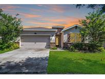 Charming single-story home with a well-manicured lawn and attached two-car garage, set against a colorful sunset sky at 405 E Freesia Ct, Deland, FL 32724