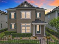 Charming two-story home featuring a manicured lawn, complemented by vibrant flowerbeds and a secure, decorative black metal fence at 473 Oviedo Blvd, Oviedo, FL 32765