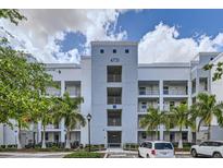 Exterior of a modern condo building with palm trees and well-manicured landscaping on a partly cloudy day at 4731 Clock Tower Dr # 105, Kissimmee, FL 34746