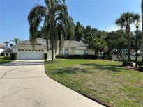 Charming single-story home with a well-manicured lawn, mature palm trees, and a two-car garage at 5604 Loma Vista W Dr, Davenport, FL 33896