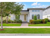Charming single Gathering home showcasing a modern architectural style, professional landscaping, and a bright yellow front door at 7789 Nemours Pkwy, Orlando, FL 32827