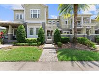 Inviting townhome with manicured landscaping, lush green lawn, and a stone pathway leading to the front entrance at 8436 Tavistock Lakes Boulevard, Orlando, FL 32827