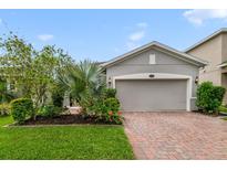 Charming single-story home featuring a brick driveway and a manicured lawn with colorful flowers and lush greenery at 1396 Riley Cir, Deland, FL 32724