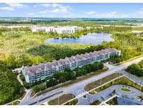 Stunning aerial view of the condo building complex featuring a serene lake and lush green surroundings at 14200 Avalon Rd # 409, Winter Garden, FL 34787
