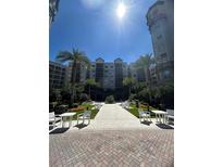 Beautiful courtyard featuring a walkway, multiple benches and tables, lush palms and a modern building in the background at 14501 Grove Resort Ave # 3636, Winter Garden, FL 34787