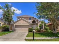 Two-story home with a front-facing two-car garage, manicured lawn and established trees at 2903 Joseph Cir, Oviedo, FL 32765