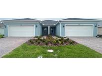 Charming attached villa featuring an attached two-car garage, landscaped yard, and brick paver driveway at 5158 Gardenrow Dr, St Cloud, FL 34772