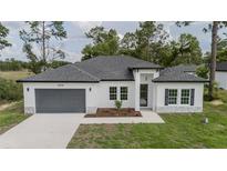 Charming single-story home features a gray garage door, white exterior, and well-maintained front yard at 6054 Sw 154Th Place Rd, Ocala, FL 34473