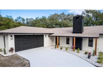 Charming home featuring a two-car garage, black trim accents, and a brick chimney at 817 Helen Ave, Deland, FL 32720
