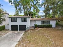 Charming two-story home with a two-car garage, black trim, and mature trees offering ample shade at 913 Moss Ln, Winter Park, FL 32789