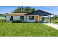 Charming single-story home with well-maintained lawn, freshly painted in white with yellow door and convenient carport at 1105 Valencia Ave, Haines City, FL 33844
