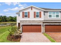 Charming townhome with stone accents, brick driveway, and a two-car garage overlooking beautiful landscaping at 4829 Cedar Bay Ter, Kissimmee, FL 34746