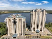 A stunning aerial view showcases two modern high-rise buildings near a tranquil waterfront setting and ample parking at 13427 Blue Heron Beach Dr # 1907, Orlando, FL 32821
