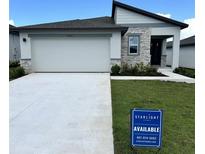 Charming single-story home featuring a stone facade, a two-car garage, and a well-manicured lawn at 1392 Dalkeith Cv, Sanford, FL 32771