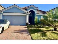 Charming home with a two-car garage, red brick driveway, and well-maintained landscaping at 1474 Lakeside Ave, Davenport, FL 33837